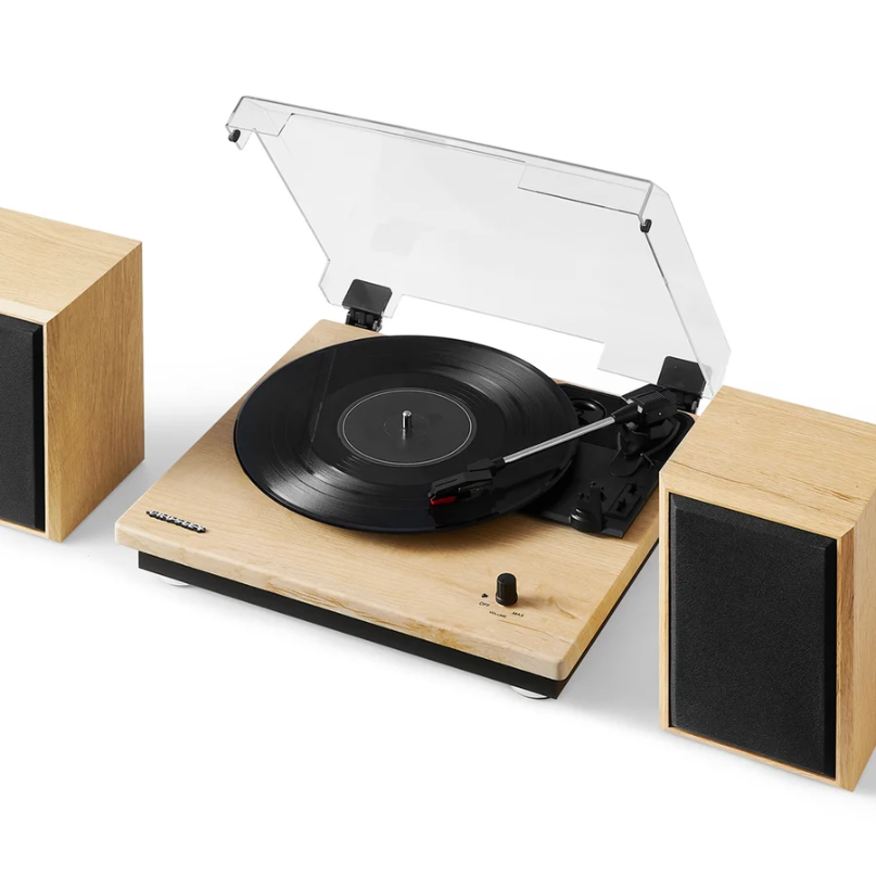 Crosley Brio Record Player Shelf System With Speakers The crosley brio record player shelf system with speakers, featuring a wood-finish turntable with a transparent dust cover that’s playing a vinyl record, is accompanied by two matching speakers with black fronts.